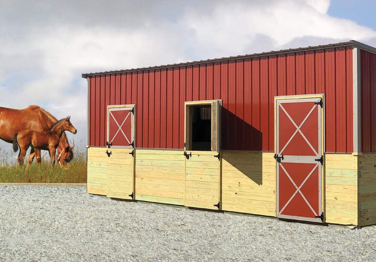 Red livestock shelter with tack room and horses grazing in the background