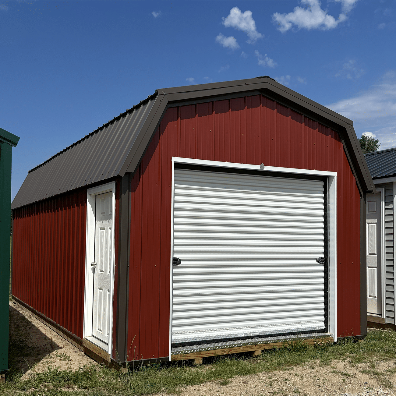 Red metal lofted garage with white roll up door