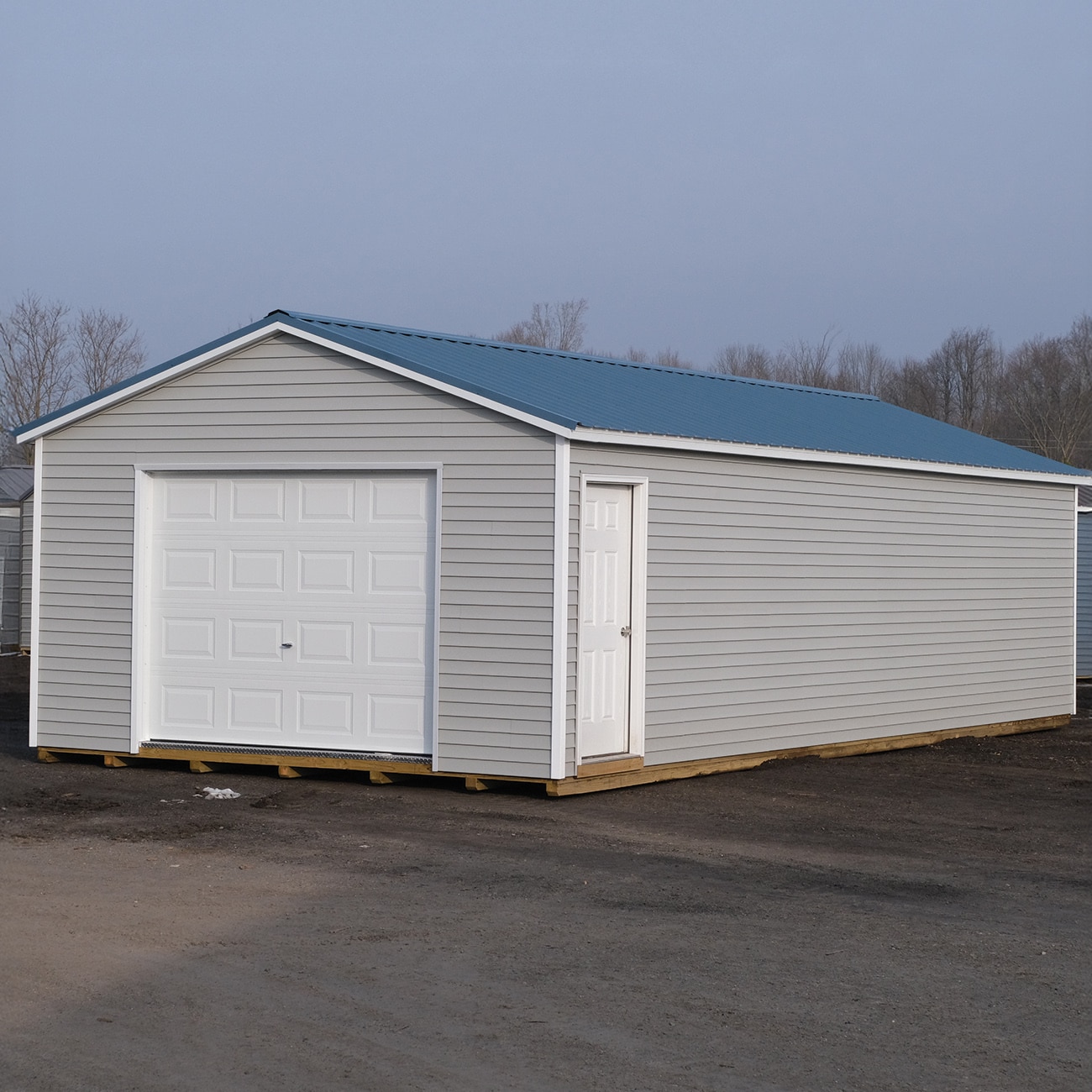 Vinyl sided grey gable portable garage on the lot at Mid Michigan Barn's headquarters in Evart, MI.